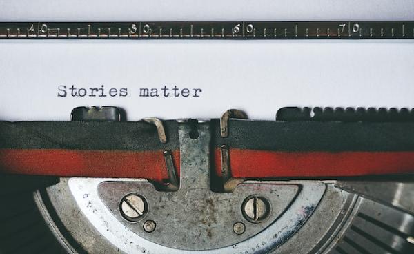typewriter with paper saying "stories matter"