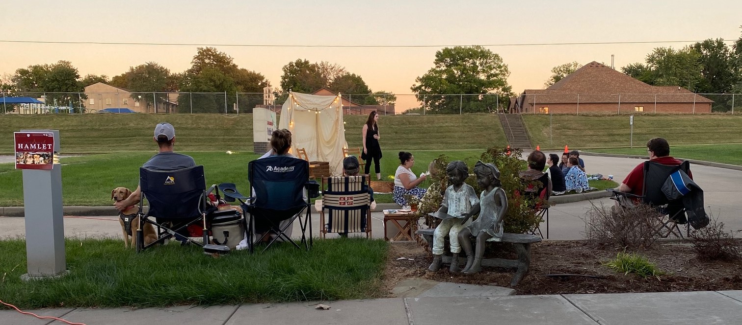 During a sunset evening patrons camp out on the library's front lawn while members of Stone Soup Shakespeare perform Hamlet.