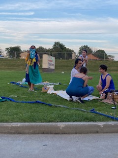 The cast of Stone Soup Shakespeare, dressed in blue costumes, put on a performance of Pericles on the library's front lawn.