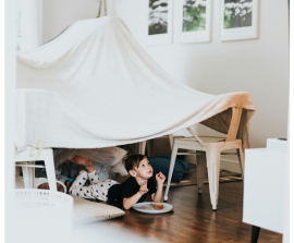 little boy sitting under a fort made with sheets