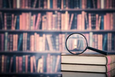 A magnifying glass in front of a wall of books