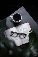 Image of a cup of coffee, glasses, and a book.