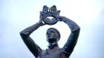 A statue of a young man places a crown on his own head.