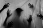 A grayed-out white sheet with the dark shadowed silhouette  of hands pressing against it. Gives a creepy vibe.